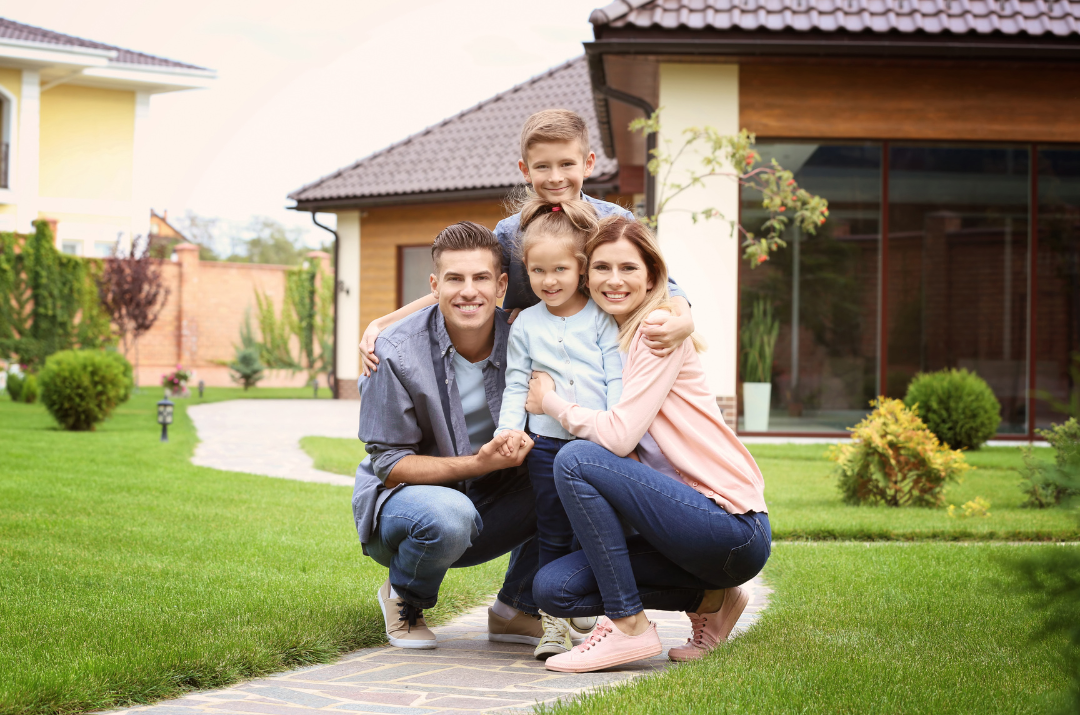 Family of four squatting down in front of a house