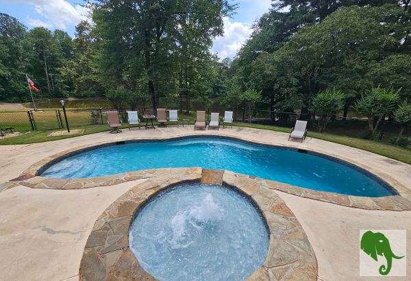 Pool area with pool, fountain, and chairs around pool with fencing around it all