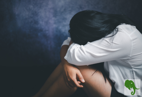 Woman sitting, balled up, distraught 