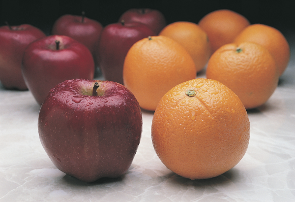 apple beside an orange with more of each in the background