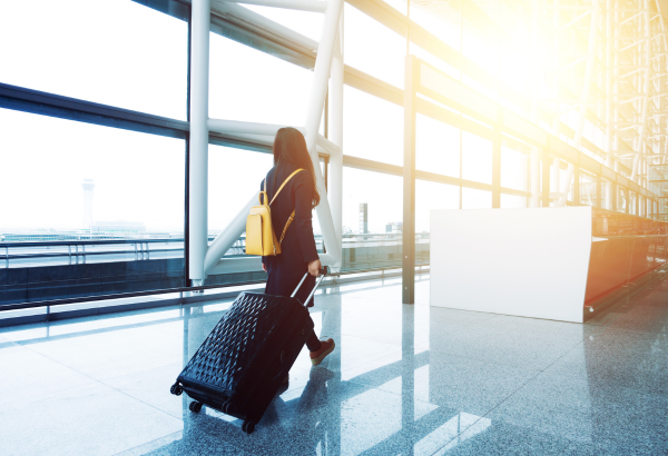 woman walking through airport terminal with suitcase in tow