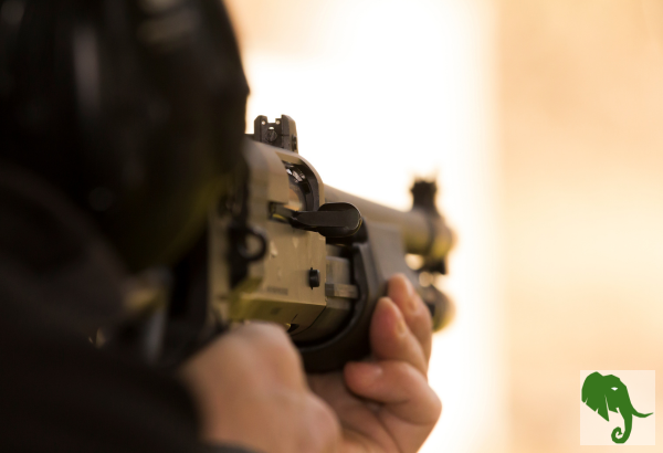 up close of someone pointing a shotgun down range