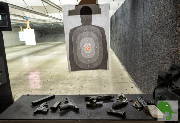 Pistols on a bench and a target hanging up out in front at an indoor range