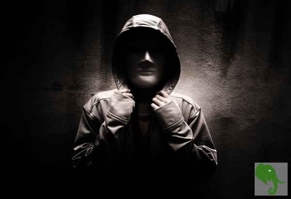 Someone wearing a hoodie with the hood up and glove on appearing threatening